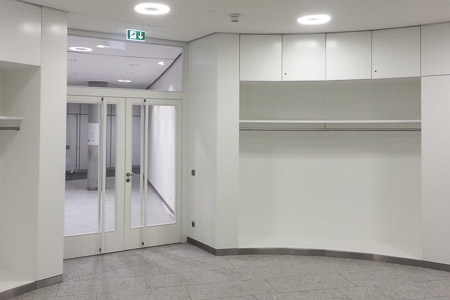 Blick in eine Garderobe mit Kleiderstangen und abschließbaren Fächern.