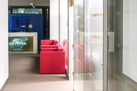 Vom Flur Blick auf den Wartebereich mit roter Couch.